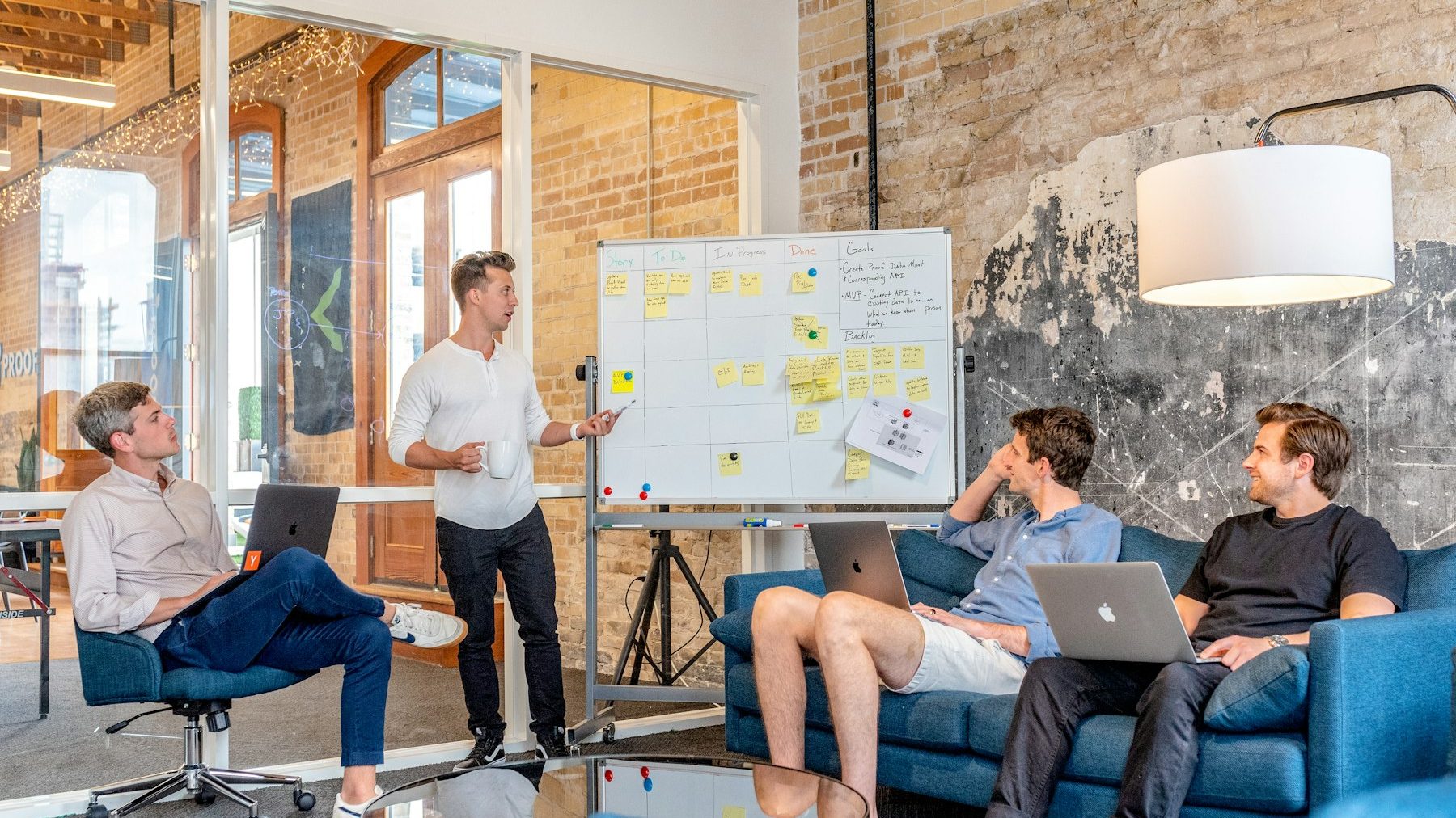 BigCommerce to Shopify migration: three people on laptops watching a colleague beside a whiteboard